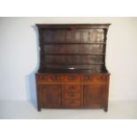 A Georgian oak dresser with six drawers, two cupboards and shelved section above