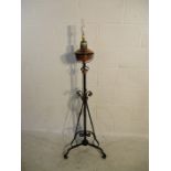 A floor standing brass lamp on decorative wrought iron stand H144cm