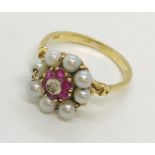 An 18ct gold ring with a central diamond, cluster of rubies surrounded by seed pearls