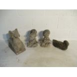 A collection of four small concrete garden ornaments including a young boy and girl holding pets,