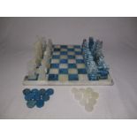 A blue and white marble chess set along with matching gaming counters (one missing)