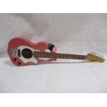 An Aria pink six string travel guitar with built in amp - serial number C8110654
