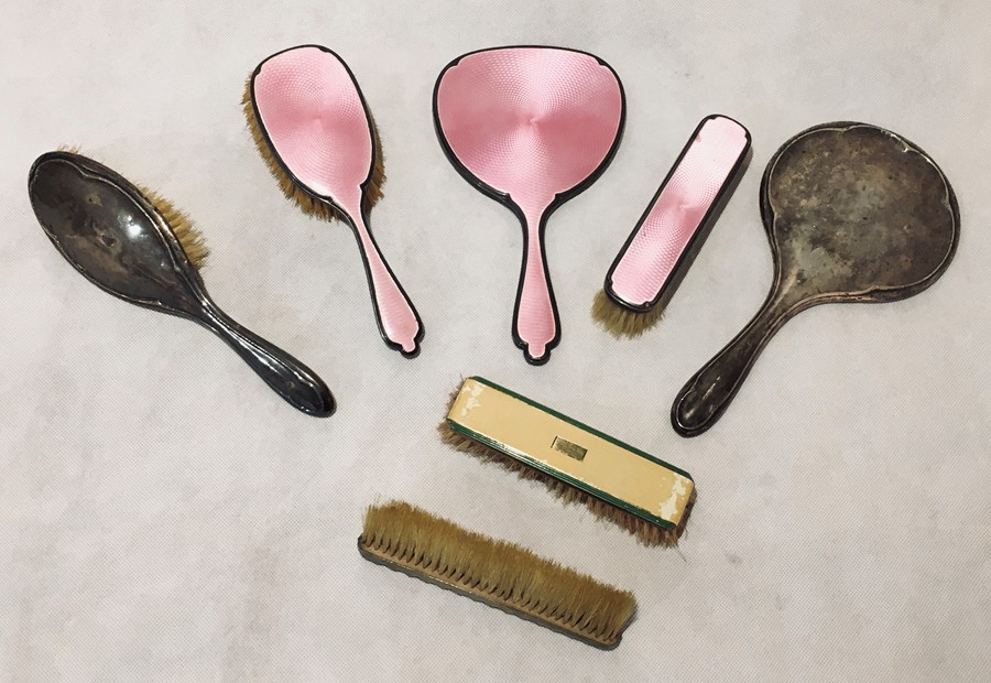 A pink guilloche enamel hallmarked silver part dressing set consisting of a mirror and two brushes,