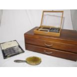 A wooden canteen of cutlery with two drawers (incomplete set) along with a silver backed brush,