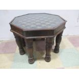 An octagonal Indian coffee table with glass top and brass decoration on eight turned legs.