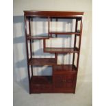 A Chinese hardwood freestanding display cabinet with open shelves, cupboard and two drawers,