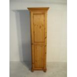 A narrow pine cupboard with integral shelving