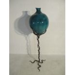 A large glazed pottery urn on intertwined wrought iron sculptural stand