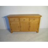 An oak sideboard with three drawers and two cupboards