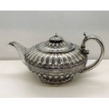 A Georgian hallmarked silver teapot of circular form, part-fluted design, leaf decoration to