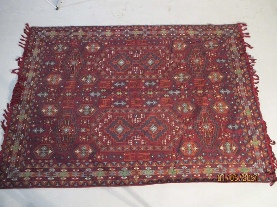 A red ground rug/wall hanging, approx. 7 ft x 5 ft