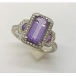 An 18ct white gold ring set with an emerald cut amethyst with a surround of diamonds and fancy cut