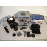 A collection of various cameras including an Olympus E-10, Panasonic video, camera (SDR-S26), Canon,