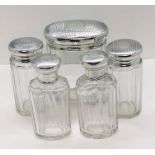 A set of five dressing table/scent bottles with hallmarked silver lids- all London 1928