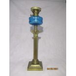 A Victorian oil lamp with brass Corinthian column supporting a blue glass well