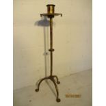 An ecclesiastical style candle stick on tripod legs.