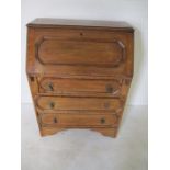 An oak bureau with Jacobean style detailing with three drawers.