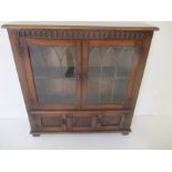 A oak bookcase with leaded glazed Gothic style panels with cupboards under