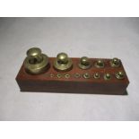 A set of brass weights in wooden holder