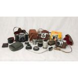 A collection of vintage cameras and lenses including Kodak, Brownie, Pratika etc.
