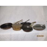 A collection of copper pans, some with brass handles