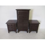 A modern dark wood chest of five drawers, along with two matching bedside cabinets