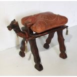 A vintage camel stool with leather seat and carved frame