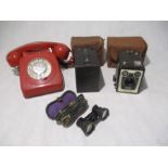 A vintage red telephone, along with a pair of cased opera glasses and two Brownie camera's