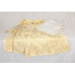 A vintage Christening gown with embroidered detail along with a vintage tablecloth and feeding