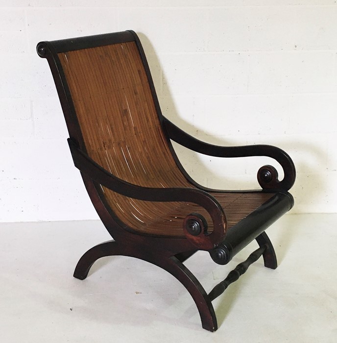 A plantation style chair with scroll arms and curved bamboo seat