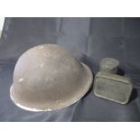 A military helmet, plus an emergency ration tin and a cigarette case.