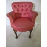 An upholstered button backed armchair on claw and ball feet