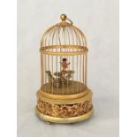 A 20th century Swiss musical bird cage, containing two feather clad birds, on the base decorated