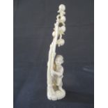 A 19th Century Japanese ivory Okimono of a young boy holding a stick by a tree containing fruit,