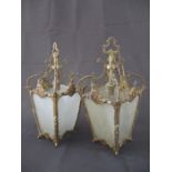 A pair of ornate gilded ceiling pendants with etched glass panels