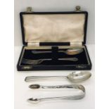 A cased hallmarked silver Christening set along with a silver pair of sugar tongs and a silver tea