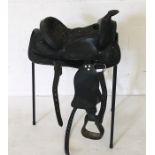 A black leather western saddle with stirrups and girth.
