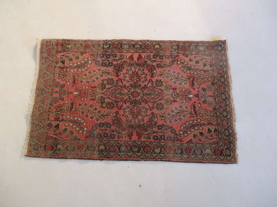 A Persian red ground rug - overall size 110cm x 70cm