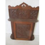 An oak wall hanging cupboard with carved detailing