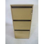 A light oak effect three drawer filing cabinet with key