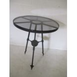 A circular glass topped garden table with metal base