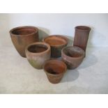 A collection of five various sized terracotta garden pots, along with one terracotta chimney -