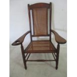 A mahogany carver with cane seating ( missing extended drop arm rest)