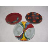 Three Poole Pottery plates with adhesive hangers to reverse