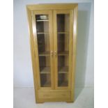 A modern oak display cabinet with single drawer under