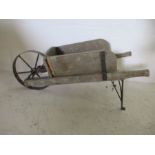 A wooden wheelbarrow planter with wrought iron wheel