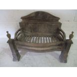 A cast iron fire basket with brass finials