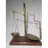 A brass balance scale on mahogany plinth