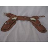 A "Texas Kid" leather holster and two cap guns with plastic moulded handles depicting steer
