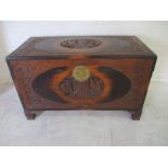 A carved camphor wood chest decorated with traditional scenes